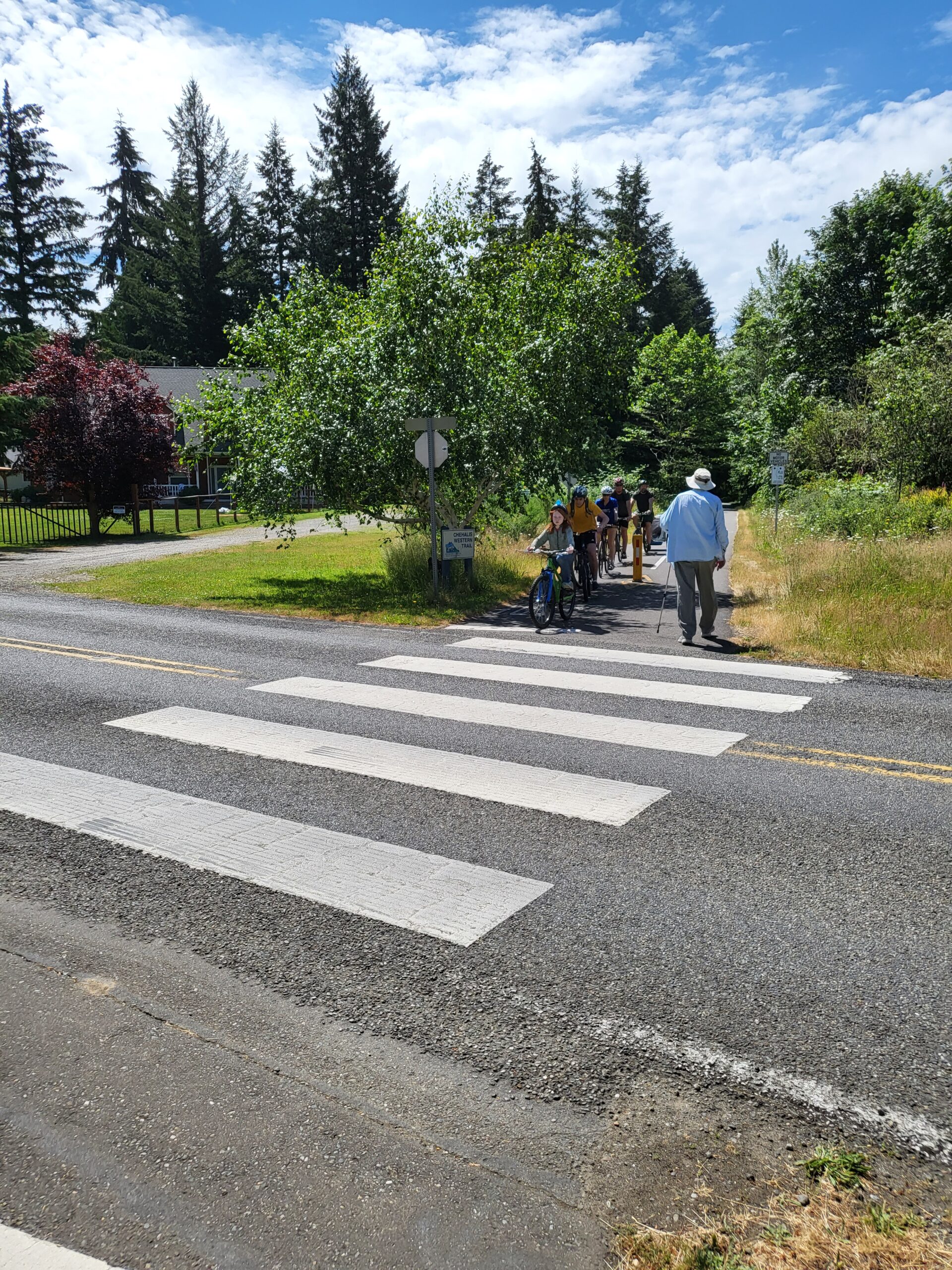 Scouts riding bikes waiting at the crosswalk.