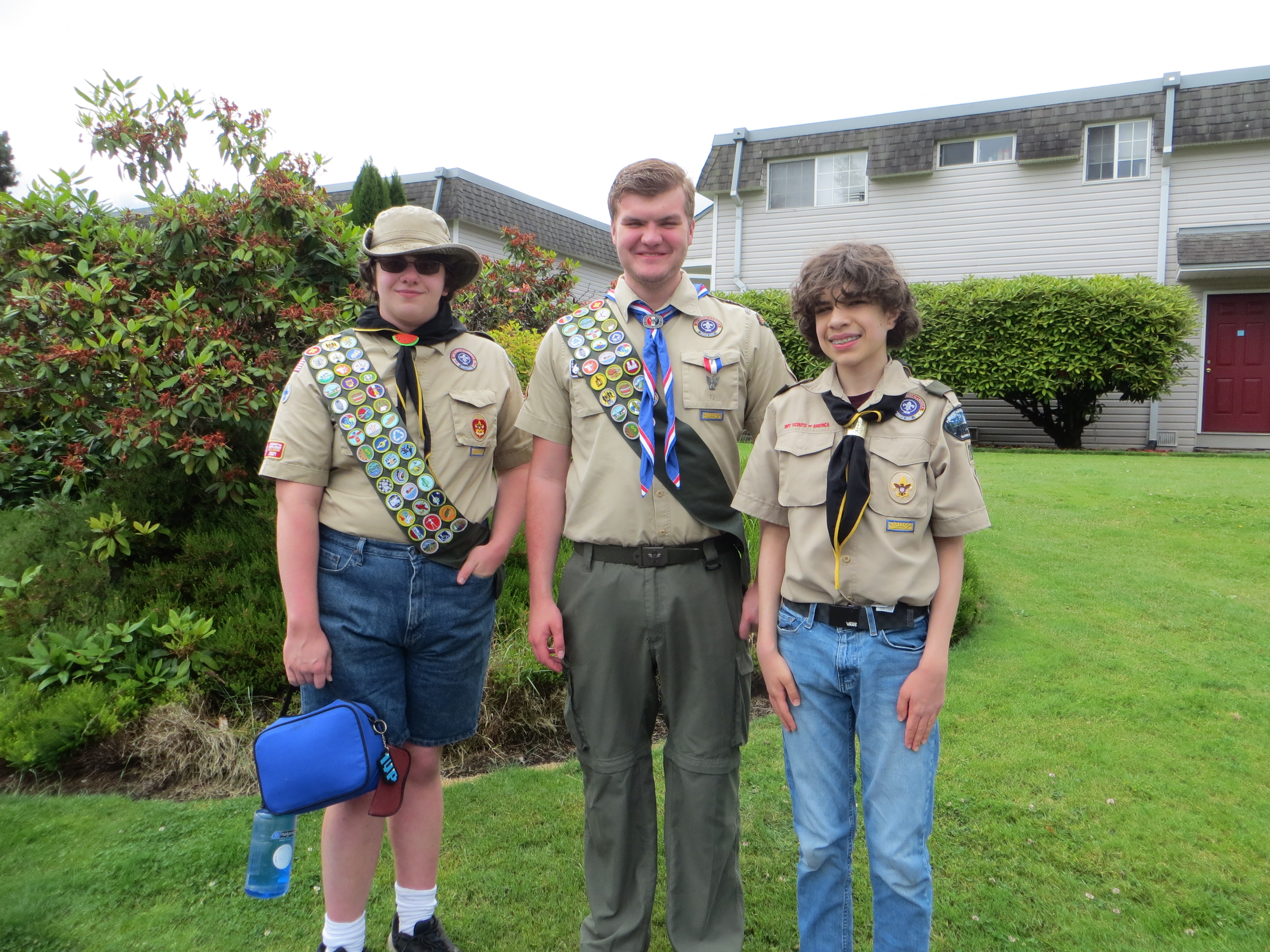 Three scouts standing in a grassy area.
