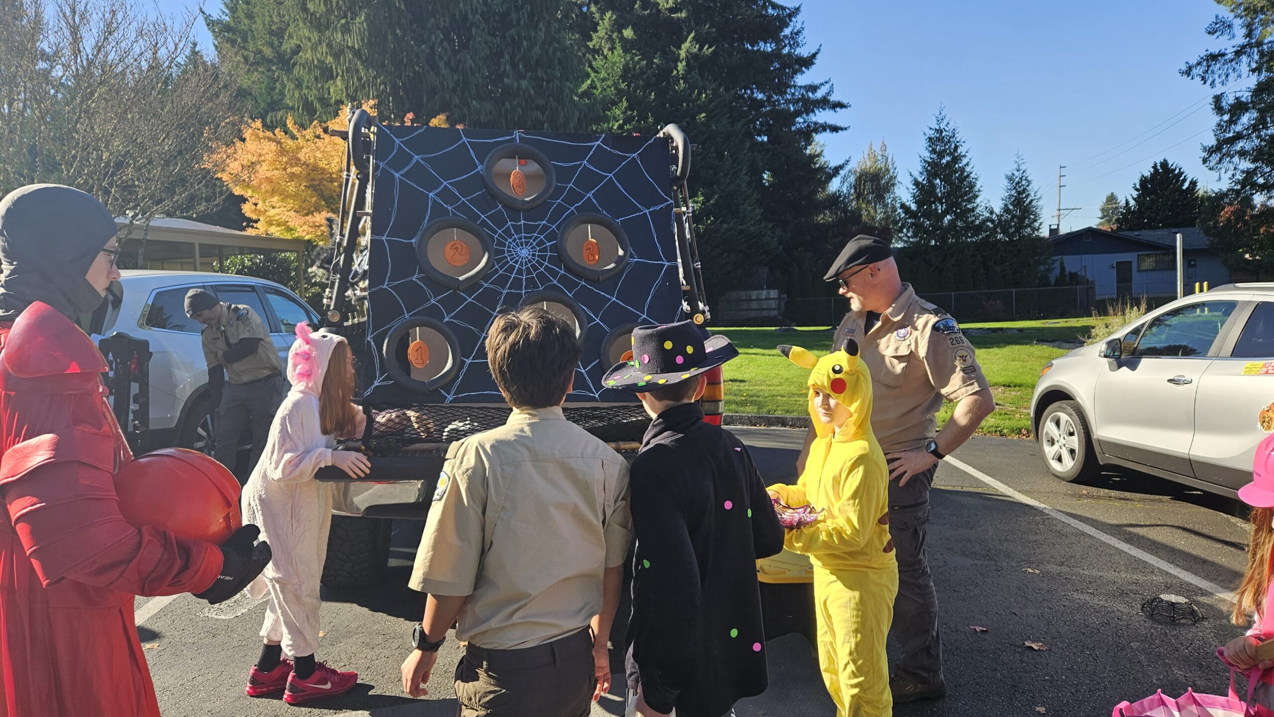 Scouts standing around a trunk with pumpkins hanging from it 